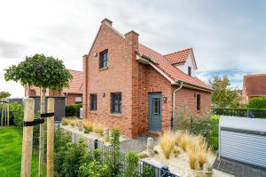 a brick house with a black door in a yard at Hus in Luv in Greetsiel