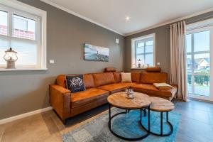 a living room with a brown couch and a table at Hus in Luv in Greetsiel +22 photos