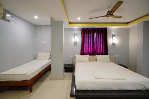 a bedroom with two beds and a ceiling fan at Hotel Sai Golden Rooms Deluxe in Tirupati