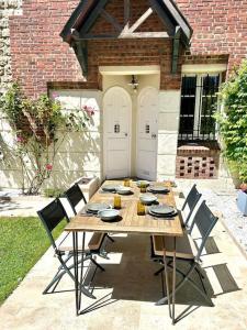 a wooden table with chairs in front of a house at Villa Marengo, jardin privatif in Trouville-sur-Mer