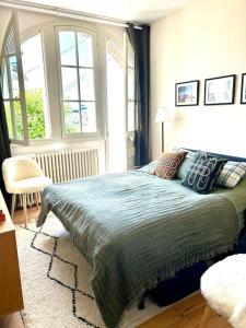 a bedroom with a bed with a green blanket and windows at Villa Marengo, jardin privatif in Trouville-sur-Mer