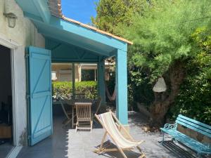 eine Terrasse mit Stühlen und einem Tisch und einer blauen Tür in der Unterkunft Maison 300 m de la plage avec un bel extérieur in Gruissan + 13 Fotos