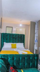 a large bed with a green tufted headboard in a room at DefiniteHomes2 - Fully furnished studio apartment with a rooftop restaurant near JKIA Airport, SGR Terminus, Downtown Nairobi in Nairobi