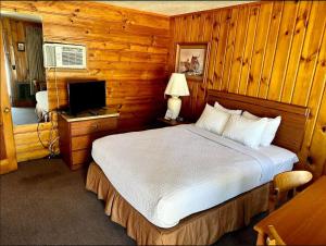a bedroom with a bed and a desk with a television at North Winds Motel in Mackinaw City