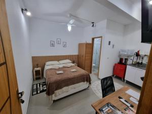 a bedroom with a bed and a table and a kitchen at Studio fantástico in São Paulo