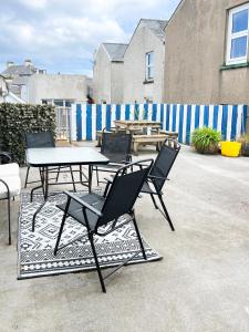 eine Gruppe Stühle, ein Tisch und ein Zaun in der Unterkunft Harbour Townhouse in Portrush