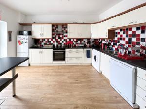eine Küche mit weißen Schränken und roten und weißen Fliesen in der Unterkunft Harbour Townhouse in Portrush