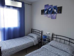 two twin beds in a room with a window at Apartment Escorpiones in Torrevieja +23 photos