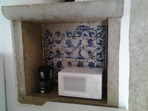 a microwave in a wall with a blue and white wallpaper at Typical small house near Lisbon in Oeiras +20 photos