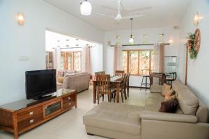 a living room with a couch and a flat screen tv at Destine Holiday Bungalow in Galle