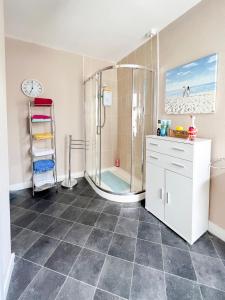 uma casa de banho com chuveiro e um relógio na parede em Station View Portrush em Portrush