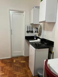 een keuken met witte kasten en een houten vloer bij Lindo Studio Flamengo in Rio de Janeiro