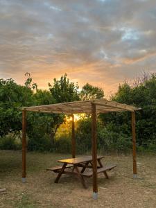 a picnic table with a wooden canopy in a field at Villa del Lupo in Santa Maria la Palma