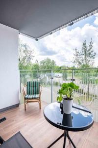a room with a table and a chair on a balcony at Blue Sun Apartament Słoneczny in Kołobrzeg