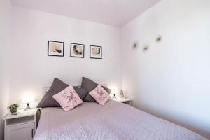 a white bedroom with a bed with pink pillows at Blue Sun Apartament Słoneczny in Kołobrzeg