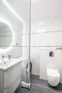 a white bathroom with a toilet and a sink at Blue Sun Apartament Słoneczny in Kołobrzeg +17 photos