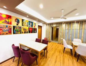 a room with tables and chairs and paintings on the wall at Havelock City Hostel, Colombo in Colombo