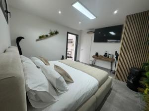 a bedroom with a large bed with white sheets and a flat screen tv at Suite Romantique Reve d Amazonie option espace Spa complet en supplément in Les Mages