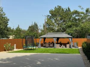 a gazebo with a table and chairs in a yard at Heaven Apartment in Hajdúszoboszló
