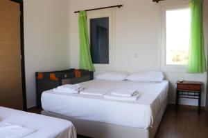 two beds in a room with green curtains at Ateni House in Agios Petros