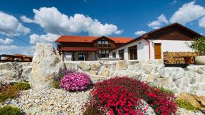 a house with flowers in front of a stone wall at Gold Horse Vendégház in Szilvásvárad
