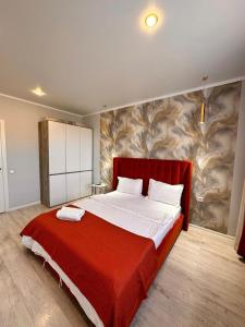 a bedroom with a large bed with a red blanket at Квартира в новом ЖК Абай in Kokshetau