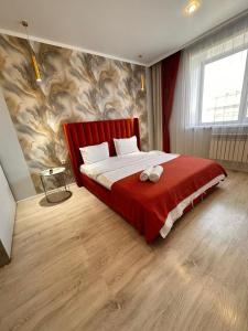 a bedroom with a large bed with a red headboard at Квартира в новом ЖК Абай in Kokshetau