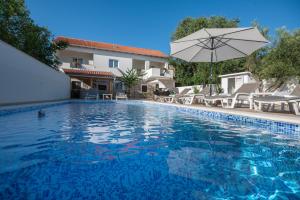 una piscina con ombrellone e sedie e una casa di Kuća za odmor IVANA a Pridraga