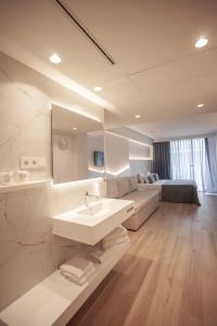 a white bathroom with a sink and a couch at Hotel Montemar Maritim in Santa Susanna