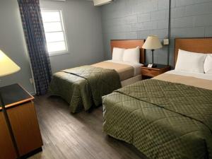 a hotel room with two beds and a window at Paradise Suites - Newport News & Jefferson Ave in Newport News