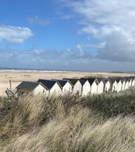 a row of beach huts on a sandy beach at Appartement dans Villa in Ouistreham
