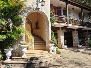 a building with a staircase and vases in front of it at Carangola Guesthouse in Petrópolis