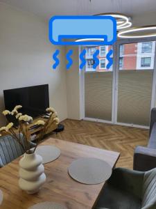 a living room with a table and a vase with flowers at Apartament w Centrum Luksusowy, Klimatyzacja, Full Opcja, Zameldowanie 24h, Duży Parking, Balkon, PlayStation 5, Ekspres, Netflix, Winda, FV, Nowy Budynek in Starogard Gdański