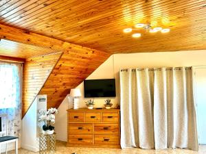 a living room with a television and a wooden ceiling at Appartement deux chambres plus une chambre bébé ou enfant maximum trois ans à la campagne au calme in Cléguérec