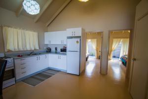 a kitchen with white cabinets and a refrigerator at Cook Islands Holiday Villas - Muri Lagoon Beachfront in Rarotonga