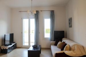 a living room with a couch and a tv at Ateni House in Agios Petros