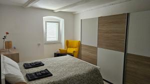 a bedroom with a bed and a yellow chair at Vila Emona in Mali Lošinj
