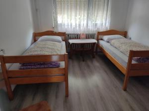 a bedroom with two beds and a table and a window at Apartman Plivsko Jezero Jajce in Jajce +9 photos