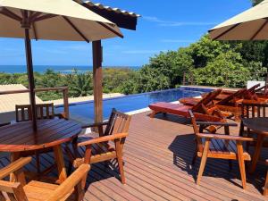 a deck with tables and chairs and an umbrella at TRANQUILA FLATS in Morro de São Paulo