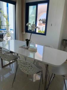 a white dining table and chairs with a flower on it at Modern 3 bedroom apartment penthouse in Paphos City +1 photo