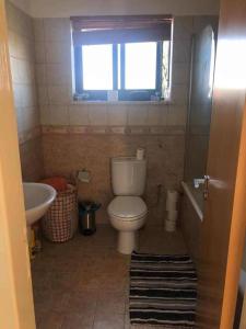 a bathroom with a toilet and a sink and a window at Modern 3 bedroom apartment penthouse in Paphos City