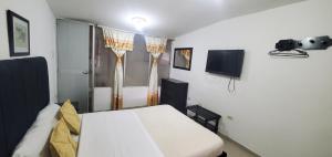 a bedroom with a white bed and a tv at Hotel Popayan Plaza in Popayan