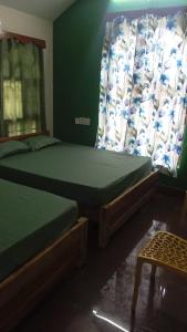 two beds in a room with a green wall at Chidambaram Spiritual Stay in Chidambaram