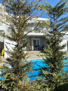 zwei Bäume vor einem Gebäude mit Pool in der Unterkunft Ammos & Thalassa Apartments in Ofrynio