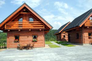 two wooden buildings with tables and chairs on a patio at Chaty NOVA pri Pieninách in Spišská Stará Ves