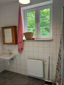ein weiß gefliestes Badezimmer mit Waschbecken und Fenster in der Unterkunft Apartament Pastelowy in Krynica Morska
