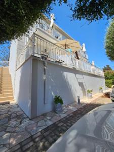 a white house with a balcony and a staircase at Natura Studios in Andipáta Erísou