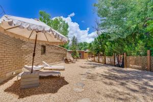 a patio with an umbrella and benches and a fence at Mid-Century Modern Taos Home with Hot Tub and Fire Pit in Taos