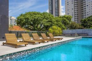 a row of chairs sitting next to a swimming pool at Studio Style - Vila Olímpia in Sao Paulo