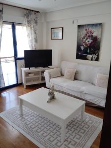 a living room with a white couch and a white coffee table at La Casina Azul de May in San Juan de la Arena